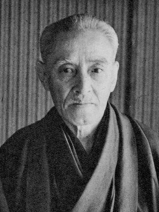 A photographic portrait of Kyuzo Mifune in judogi in later life, white-haired.